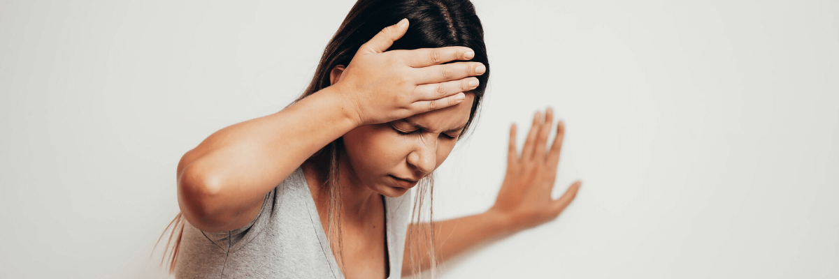 A woman holding her head in pain, experiencing a migraine.